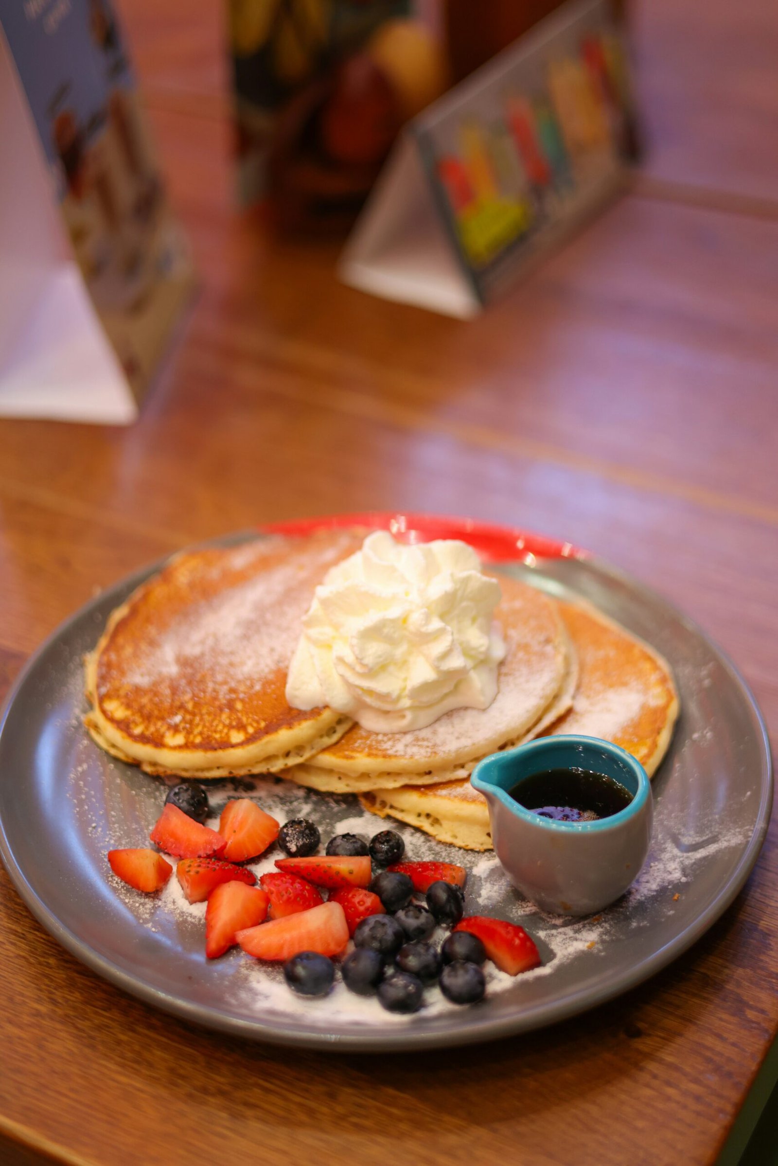 A plate of pancakes with fruit and whipped cream