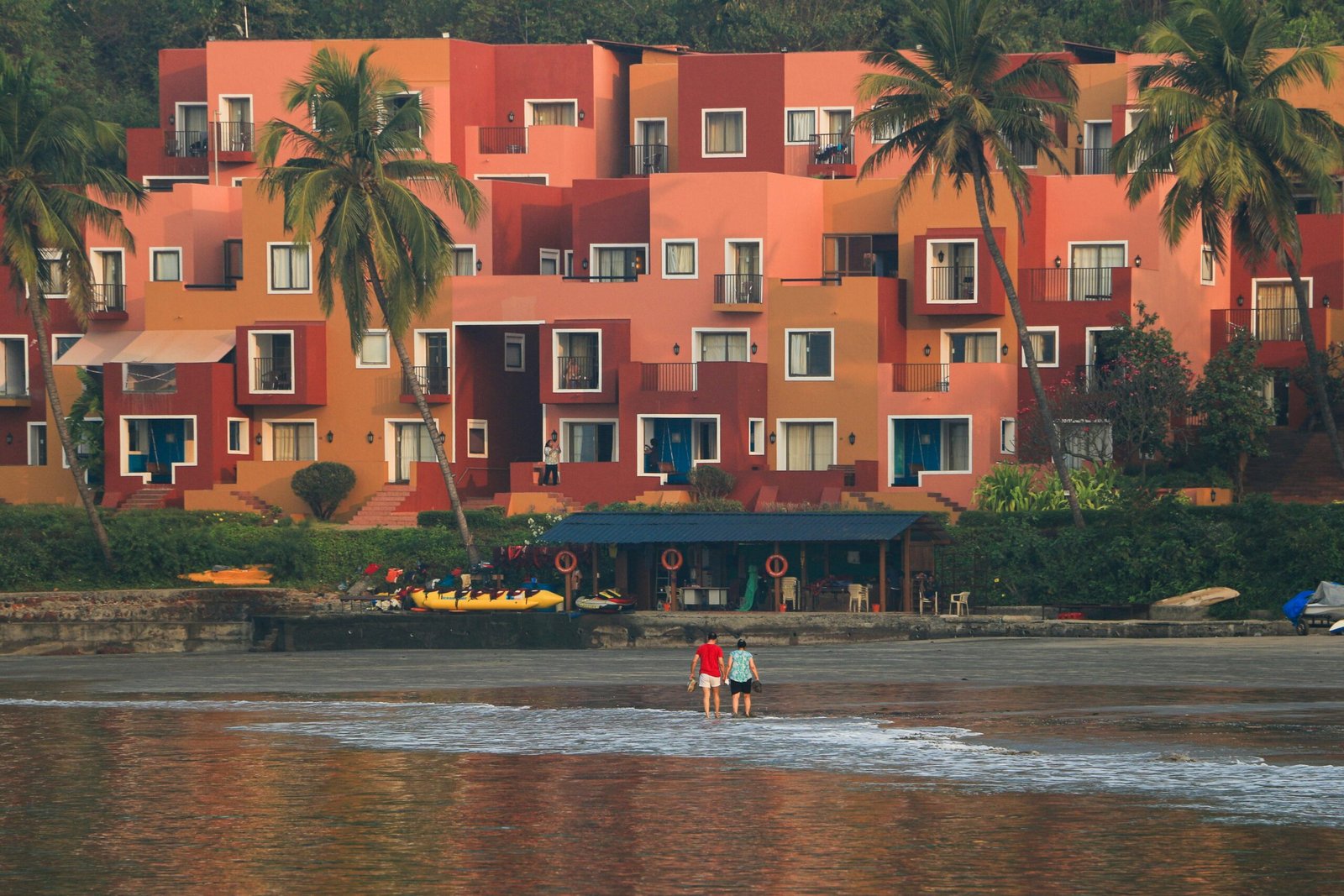 a couple of people standing on top of a sandy beach